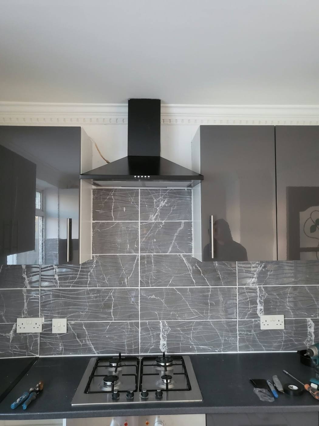 Finished kitchen with grey gloss units, marble-effect splashback and black chimney hood